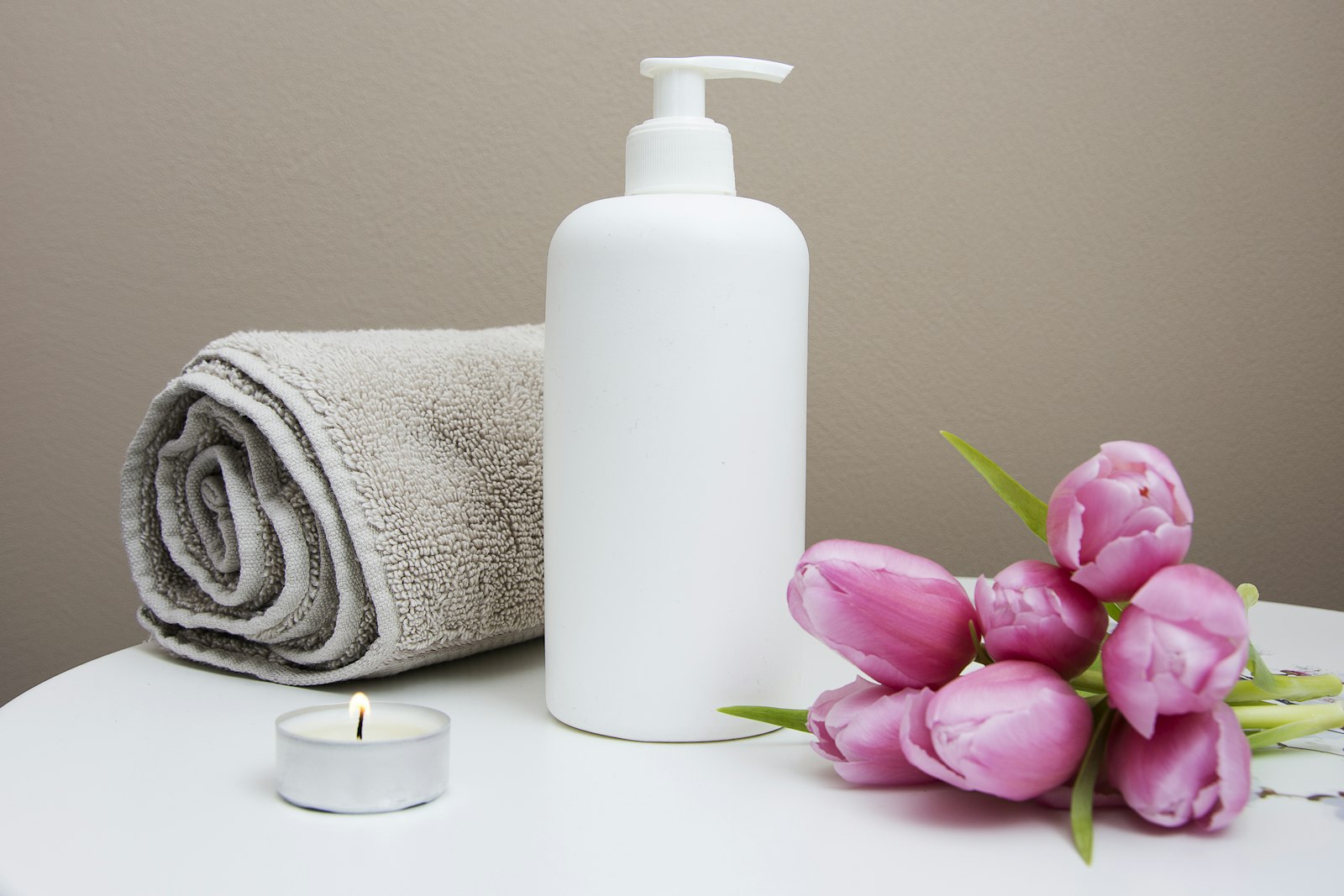 Serviette, tulipes roses et chandelle dans un décor de spa