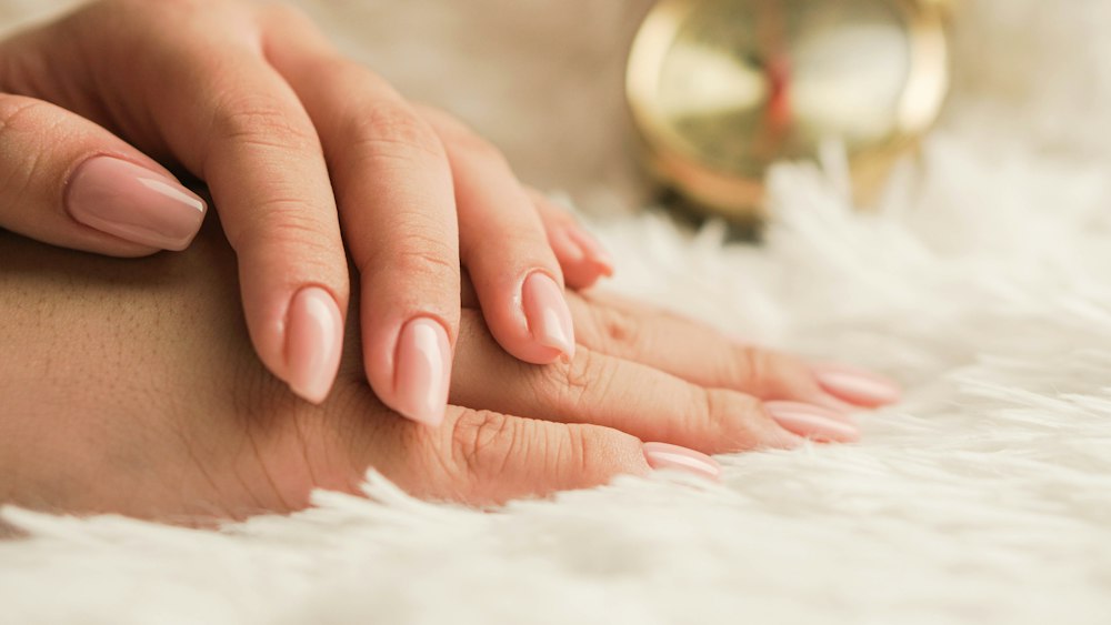 Mains aux ongles rose pâle sur un tissu doux